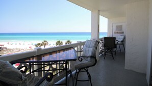 Ein Balkon mit Blick auf den Strand, inklusive Tisch und zwei Stühlen.