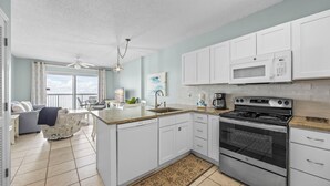A modern kitchen with white cabinets, a stainless steel stove, and a microwave. - Dog friendly beachfront condo with in/out pools (Gulf Shores)