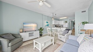 A living room with a TV, sofa, coffee table, and a dining area with chairs.