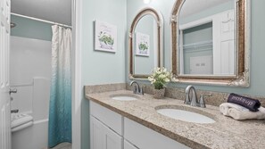 Une salle de bain avec deux lavabos, une douche, un porte-serviettes et un miroir doté d’un cadre décoratif.