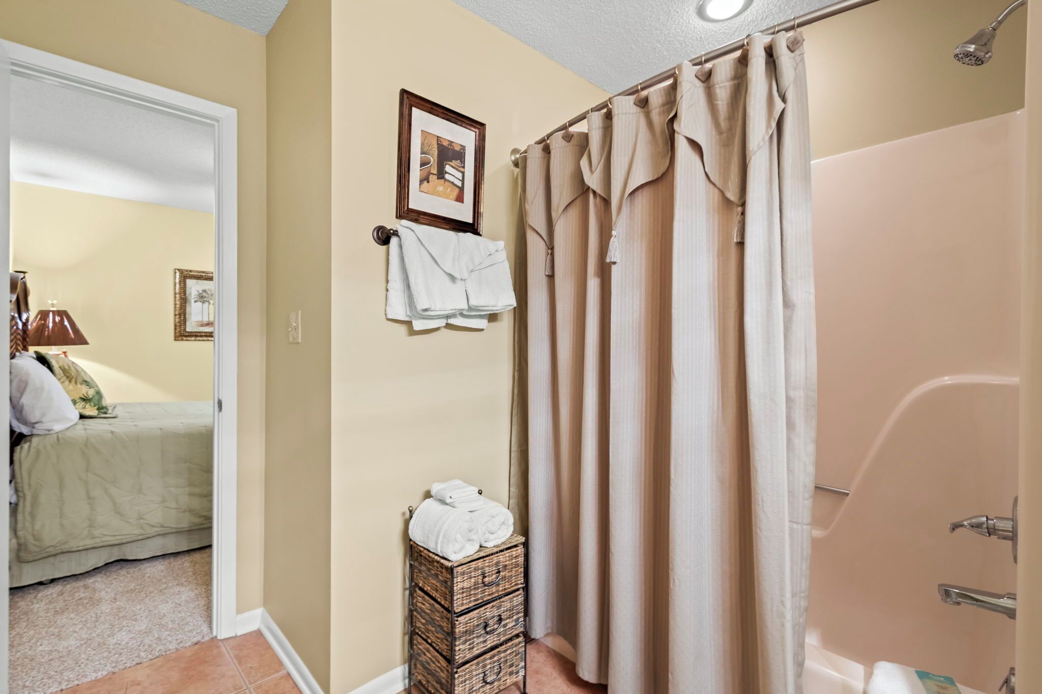 Une salle de bain avec une baignoire, une douche et des toilettes. On y trouve un porte-serviettes avec des serviettes et un tableau encadré accroché au mur.