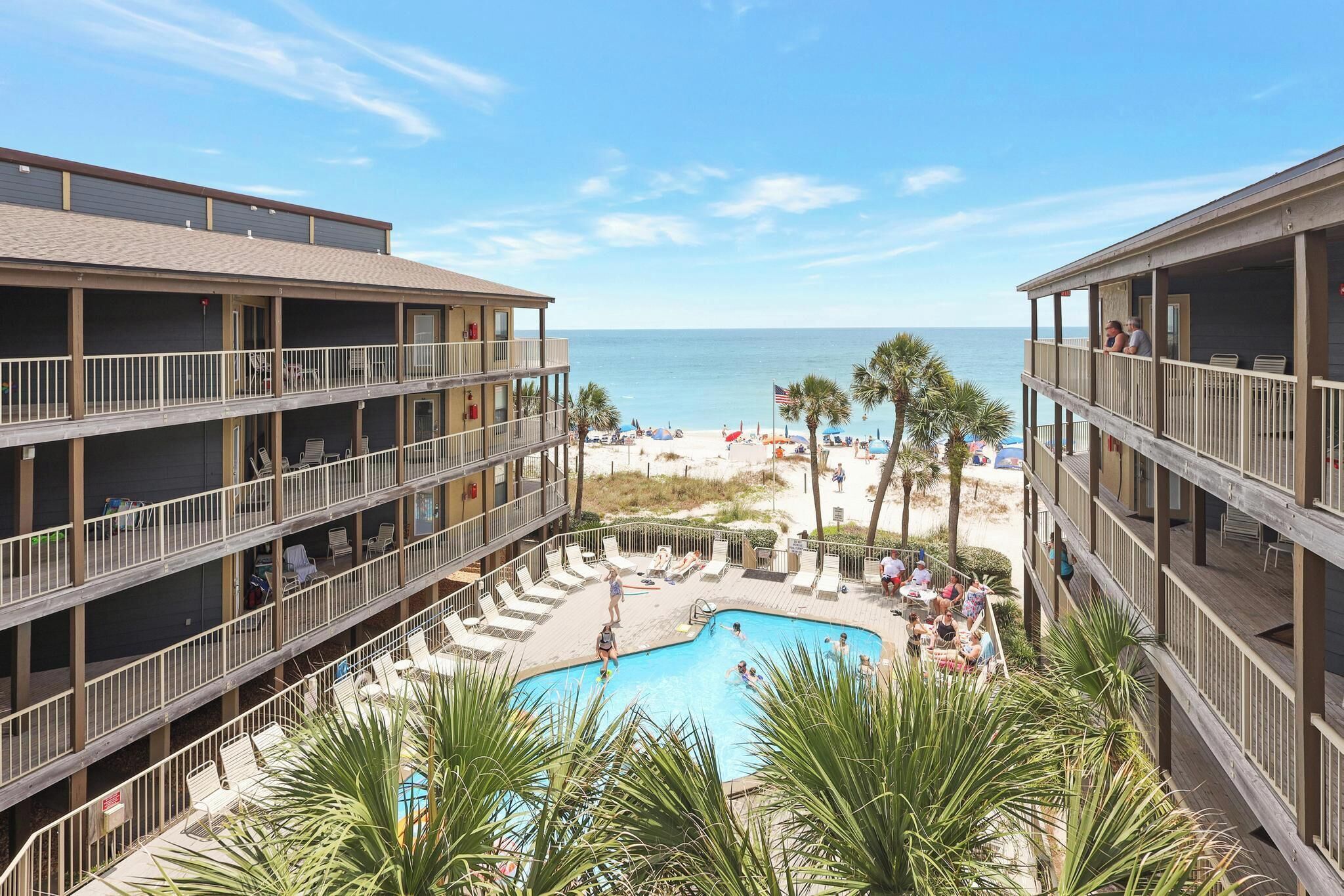 Un hotel con zona de piscina, varios balcones y vista al mar.