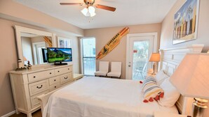 Une chambre à coucher avec un grand lit, une télévision, une commode et un ventilateur de plafond.