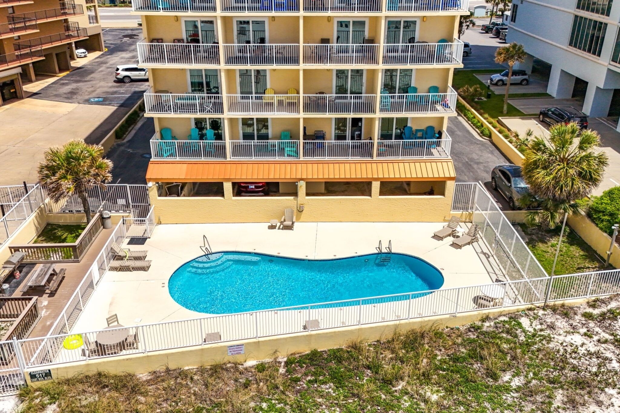 Un hotel de varios pisos con piscina en la planta baja, asientos al aire libre y vistas del entorno.