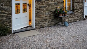 A stone building with a white door, windows with yellow lights, and a sign reading 'Hill's Barn'. - Romantic Cottage, Perranporth, Sleeps 2, Dog friendly, Walking distance to Beach (Perranporth)