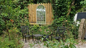 A garden patio with stone flooring, a wooden fence, and outdoor furniture. - Romantic Cottage, Perranporth, Sleeps 2, Dog friendly, Walking distance to Beach (Perranporth)