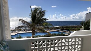 Un balcone con piscina, palme e vista sull'oceano.