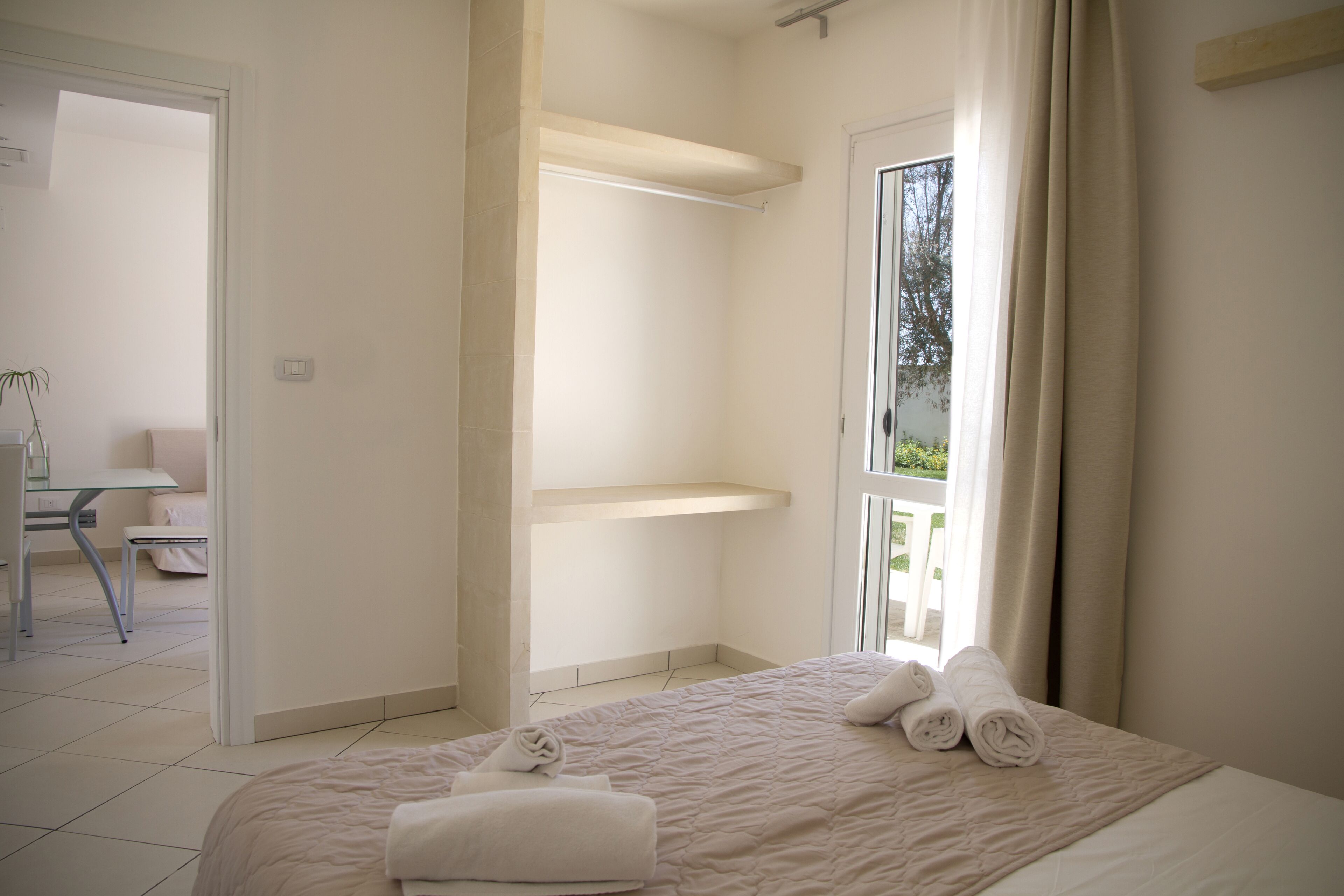 Een hotelkamer met een bed, een raam met gordijnen, een stoel en een kleine tafel.