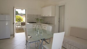 Una cocina moderna con armarios blancos, una mesa de comedor de vidrio y sillas blancas.