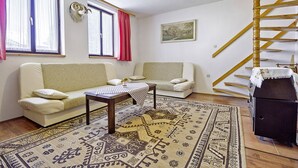 Ein Wohnzimmer mit zwei Sofas, einem Couchtisch, einem gemusterten Teppich, einer Holztreppe und einem aufgehängten Wollfellskelett.