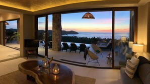 A spacious living area with a large window overlooking a scenic ocean view. - 5 Star Luxe, Ocean Views, Walk to Beach & Village, Full Staff, 8-10 BR Rates (Sayulita)