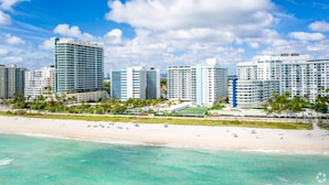 Un hotel sulla spiaggia con diversi edifici a grattacielo, una spiaggia sabbiosa e palme.