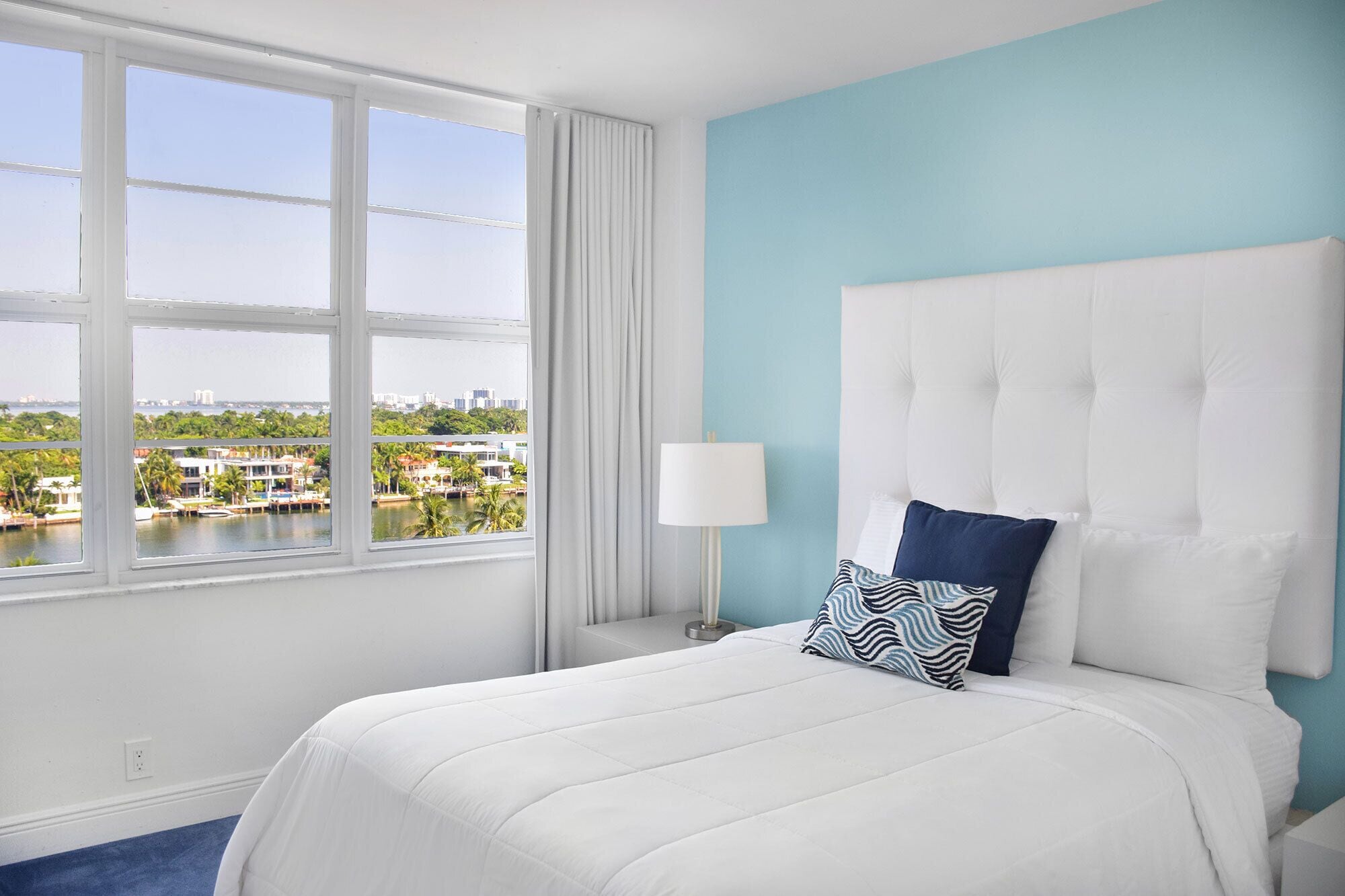A hotel room with a large bed, a view of a marina, and a cityscape.