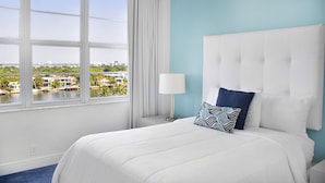 Camera d'albergo con un letto grande, vista su un porto turistico e sullo skyline della città.