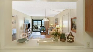 Amplia sala de estar con sofá, sillones, una mesita de centro y una mesa de comedor. Un ventanal grande ofrece vistas al exterior.