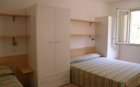 A bedroom with a bed, a wardrobe, and a window.