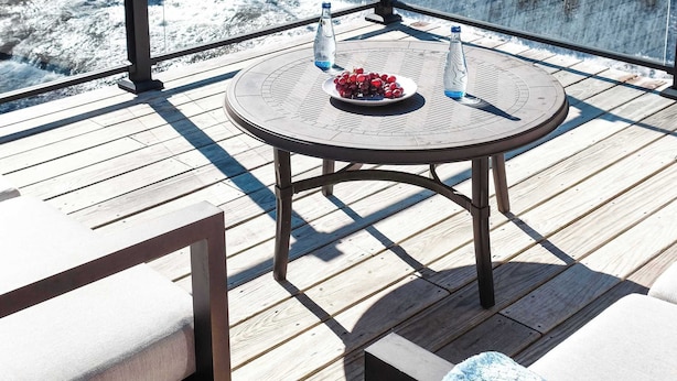Eine Terrasse mit einem runden Tisch, Stühlen und Blick auf einen Wasserfall.
