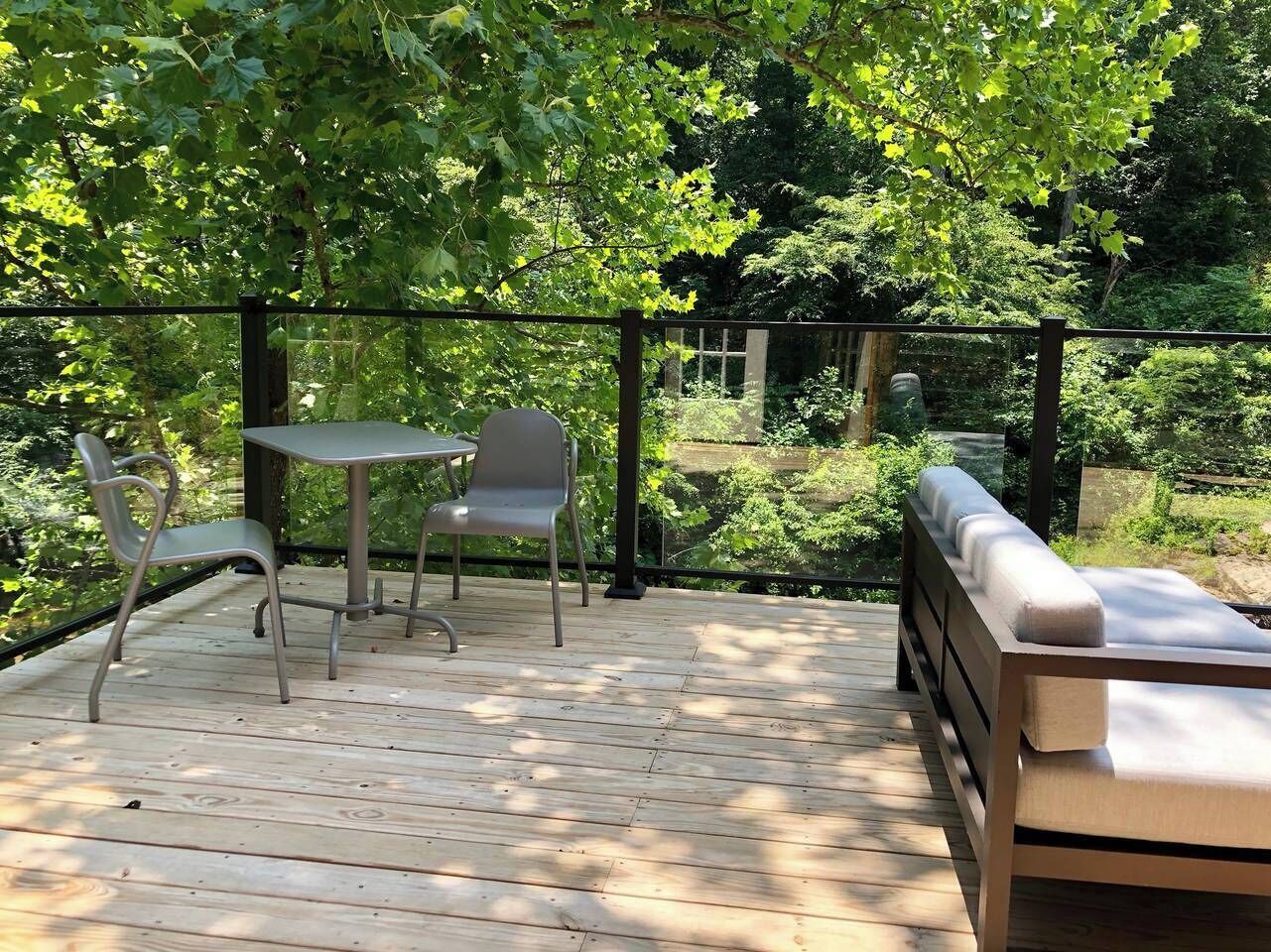 A wooden deck with a table and chairs, surrounded by lush greenery.