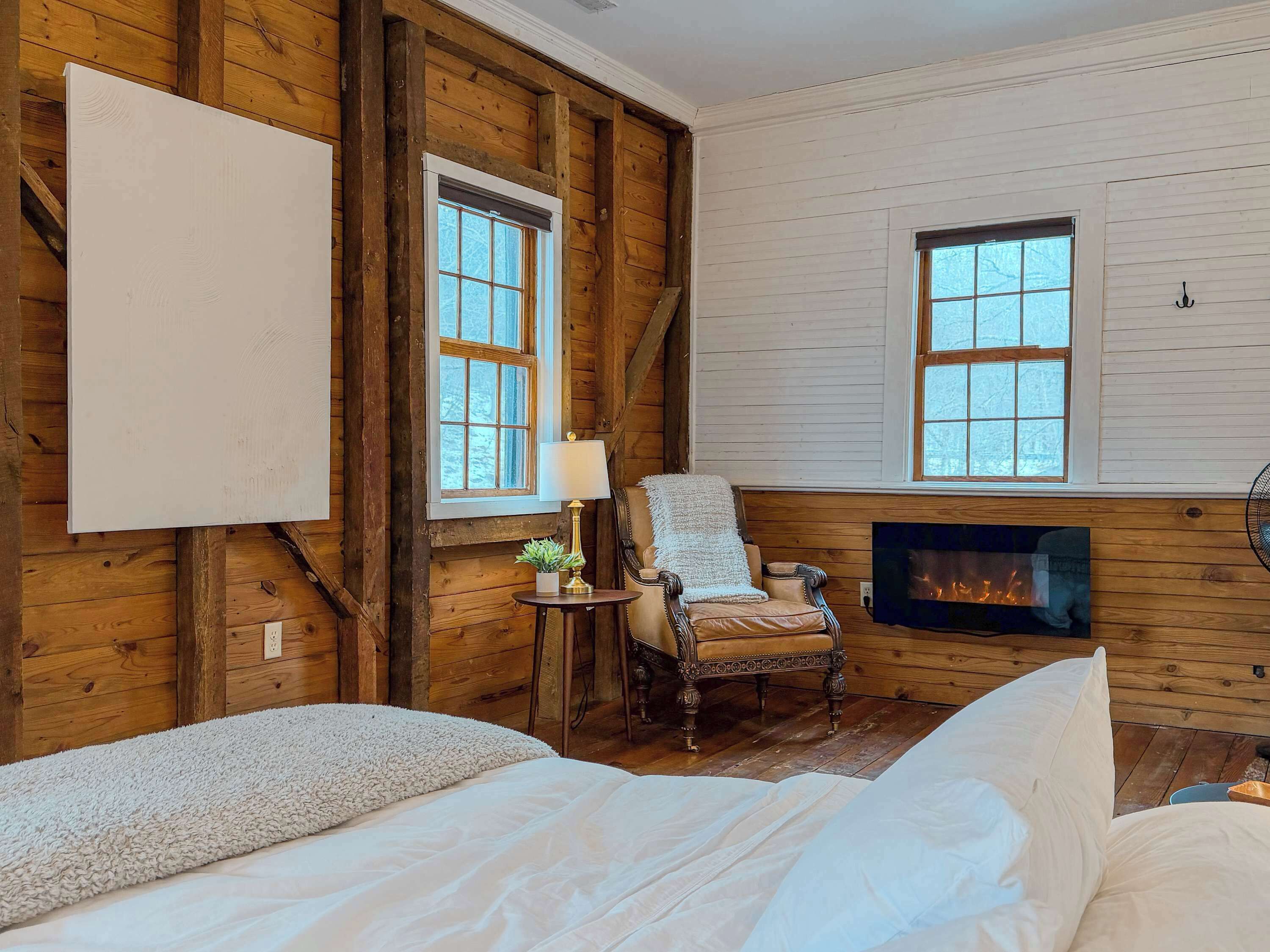 A cozy room with a fireplace, a large window, and a comfortable chair.