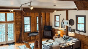 Ein gemütliches Blockhaus-Interieur mit einer Holztreppe, einem Kamin, einer Couch und einem Essbereich.
