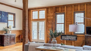 Ein geräumiges Wohnzimmer mit sichtbaren Holzbalken, einem großen Sofa, einem Holztisch und einem Kamin.