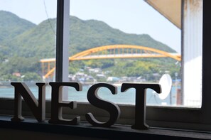 A window with the word "NEST" and a view of a bridge and mountains.