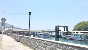 Una zona ribereña con un muro de piedra, un farol y barcos amarrados cerca de un muelle.