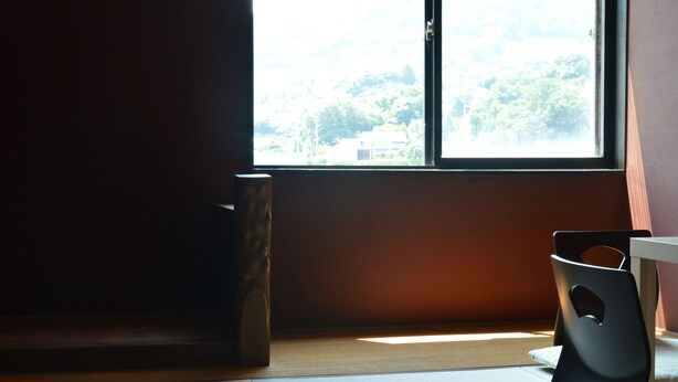 Una habitación con un ventanal grande, suelo de madera y una silla negra.