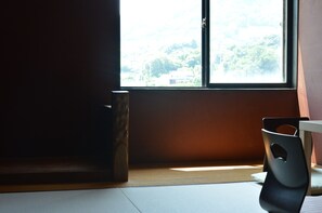 A room with a large window, a wooden floor, and a black chair. - Guesthouse NEST - Hostel (Onomichi)
