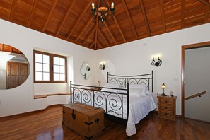 Ein Schlafzimmer mit Holzboden, einem Bett mit Metallgestell, einer Kommode und einem Nachttisch mit Lampe.
