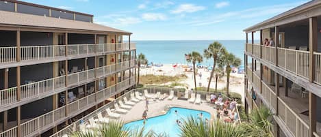 A hotel with a pool area, multiple balconies, and a view of the beach.