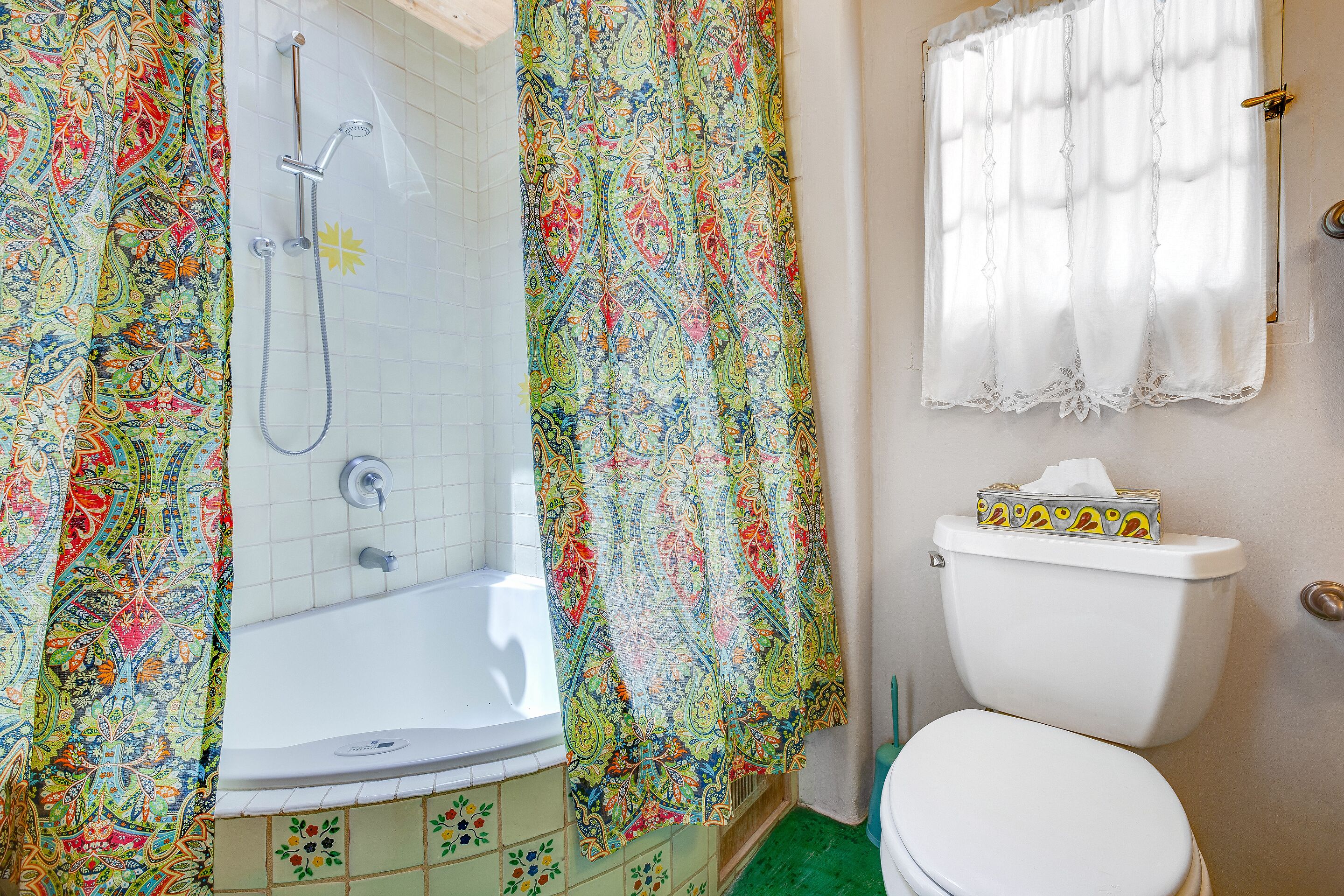 Un baño con ducha, inodoro y ventana con cortina.