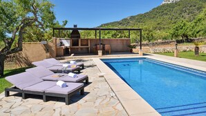A swimming pool with lounge chairs and a barbecue area. - Charming house Alou with a stunning pool, peaceful location and beautiful garden (Felanitx)