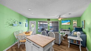 A bright green room with a dining table, chairs, a sofa, and a ceiling fan. - Awesome family beachside retreat (Gulf Shores)