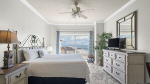 Une chambre à coucher avec un lit, une commode, une télévision et un balcon offrant une vue agréable.