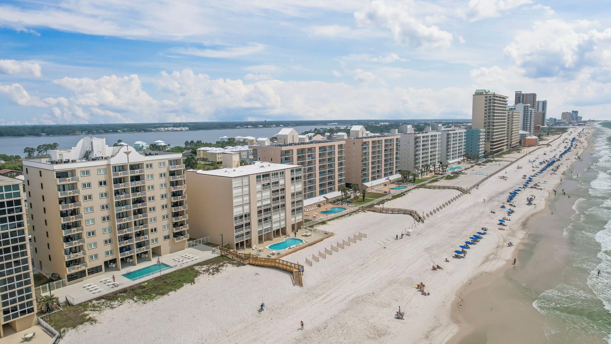 A beachfront hotel with multiple high-rise buildings, a sandy beach, and a pool area.