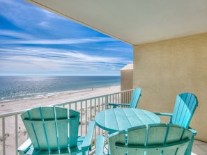 A balcony with turquoise chairs and a table overlooking a beach. - Beachfront-Walking distance to restaurants. Monthly rates for Dec thru Feb! (Gulf Shores)