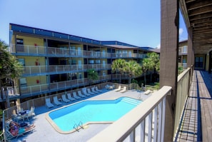 A multi-story hotel with a pool area, including lounge chairs and a small pool.