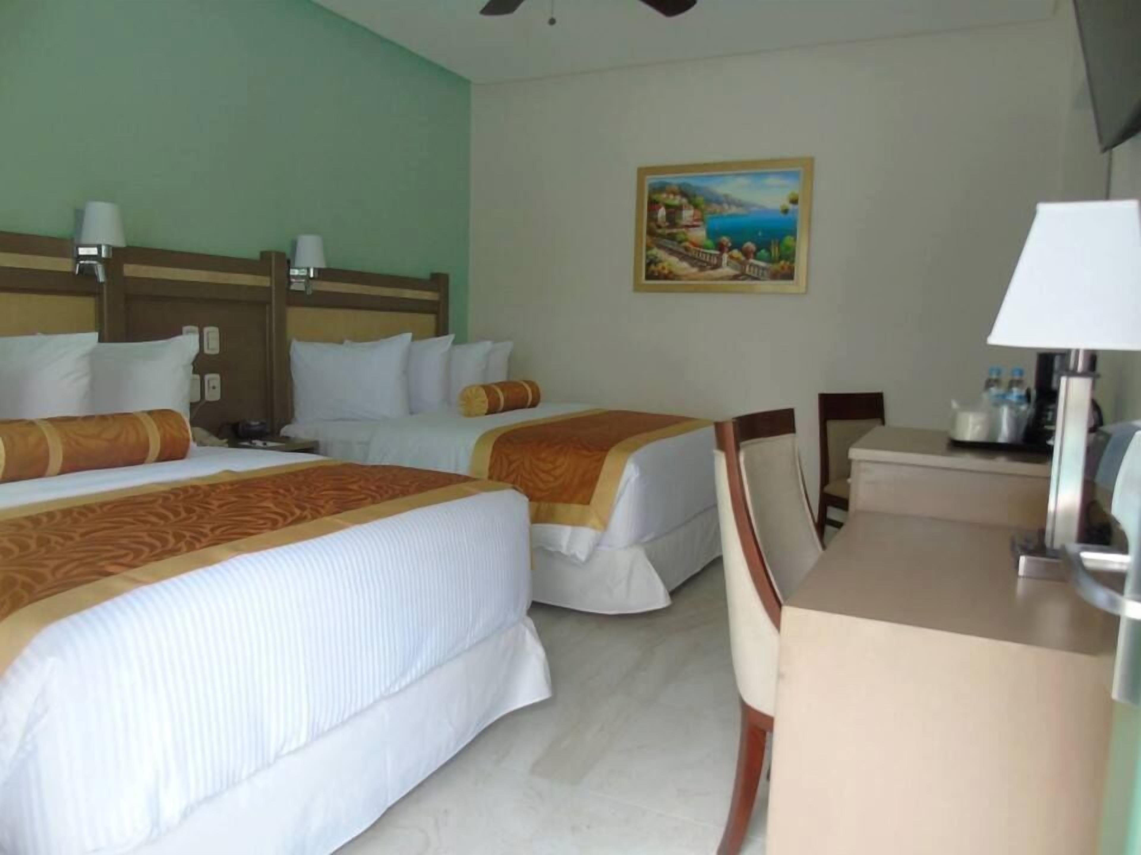 Ein Hotelzimmer mit zwei Betten, einem Schreibtisch und einem Bild an der Wand.