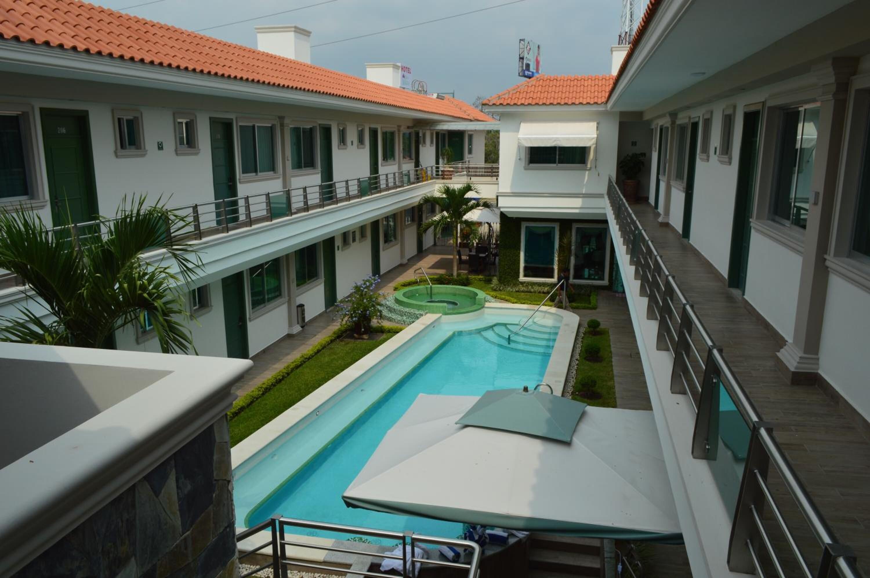 A hotel with a swimming pool, outdoor seating, and a covered area.