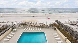 Ein Poolbereich mit Liegestühlen, einer Flagge und Blick auf den Strand.