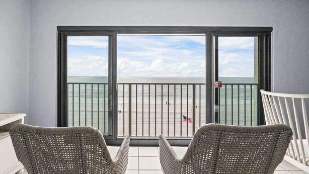 Ein Balkon mit Korbstühlen, Blick auf den Strand und ein Warnschild.