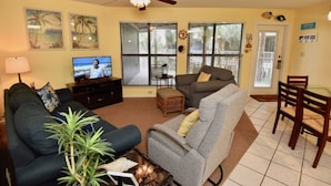 A living room with a sofa, armchair, coffee table, TV, and a ceiling fan. - 2 Bdrm family condo on the beach! (Gulf Shores)