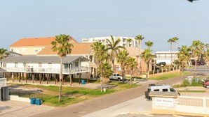 A residential street with houses, palm trees, and a street sign.