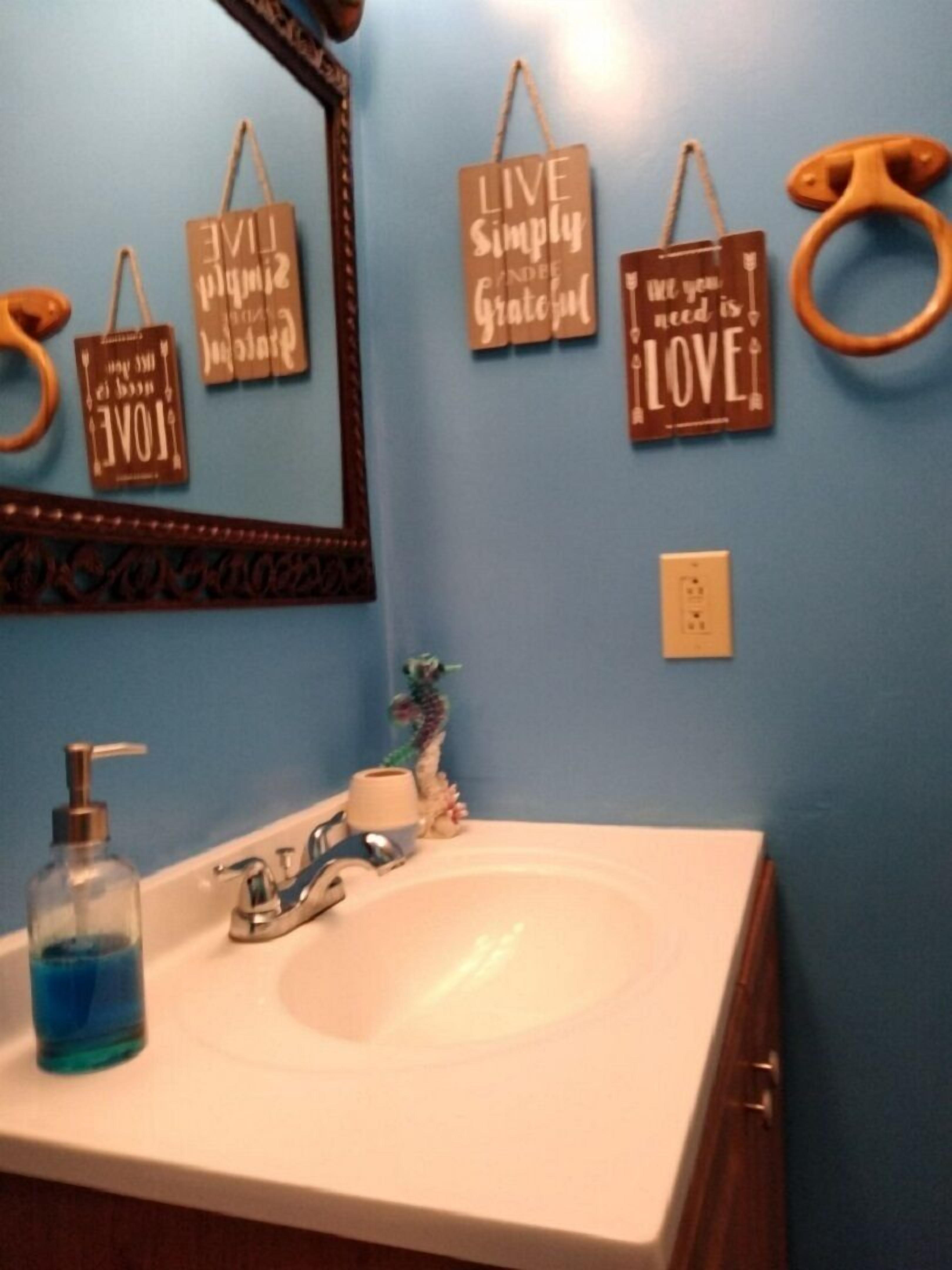 A bathroom with a sink, mirror, and motivational wall decorations.