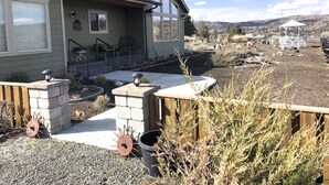 A residential house with a front porch, a small garden, and a view of a hilly landscape. - Vacation and Business Get-A-Way/Lay-Over (John Day)