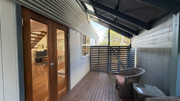 A covered deck with a sliding glass door leading to an interior space, a wooden fence, and wicker furniture. - The Osprey House - Quaint 2 bedroom cottage in the centre of town (SOUTH WEST ROCKS)