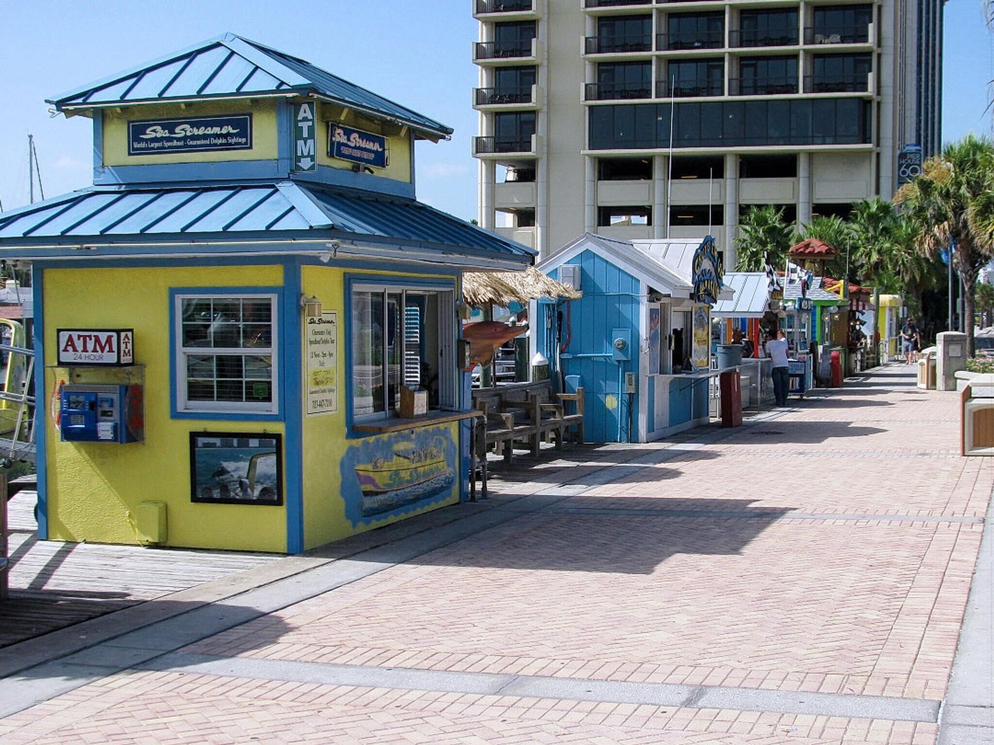 A small, brightly colored kiosk with an ATM, a sign for 'Sea Screamer', and a menu board.