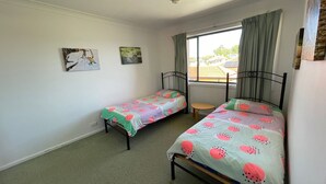 Ein Schlafzimmer mit zwei Einzelbetten, einem kleinen Tisch und zwei Bildern an der Wand.