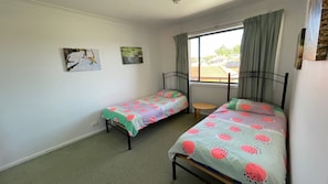 A bedroom with two single beds, a small table, and two wall-mounted pictures.